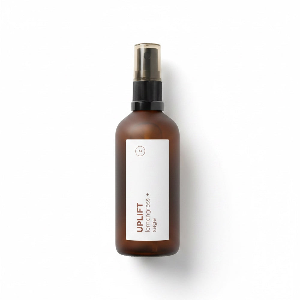 An amber glass spray bottle with a black pump and a white label next to its brown kraft paper box, both featuring the brand name UPLIFT.