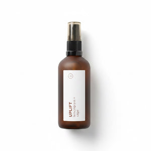 An amber glass spray bottle with a white label reading 'UPLIFT' and a black spray top, photographed on a clean white background.