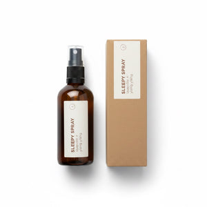 An amber glass spray bottle labeled 'SLEEPY SPRAY' stands next to its kraft paper box on a clean white background.