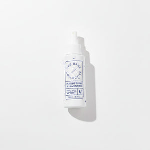 A white plastic spray bottle with a white cap, featuring a blue and white label that reads 'THE BASE COLLECTIVE' and 'MAGNESIUM & LAVENDER SPRAY'. The bottle is photographed on a clean white background with a soft shadow to the right.