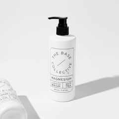 A white pump bottle of The Base Collective Magnesium Enhanced Wash with White Tea, shown on a clean white background with a second bottle partially visible in the foreground.