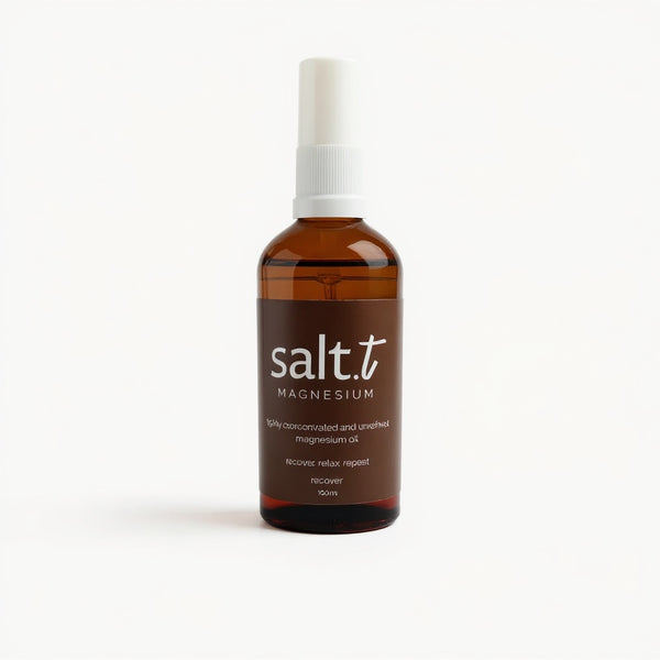 An amber glass spray bottle of salt.t Magnesium oil with a white spray cap and a dark brown label, set against a clean white background.