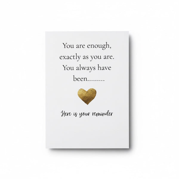 A white rectangular card or plaque with printed text reading 'You are enough, exactly as you are. You always have been.
