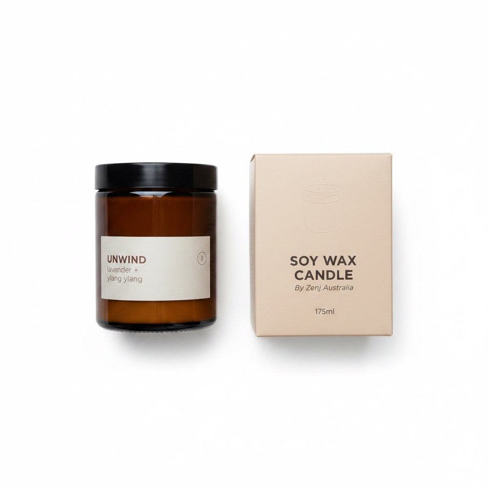 An amber glass jar candle with a black lid and a cream label next to its beige packaging box, on a clean white background.