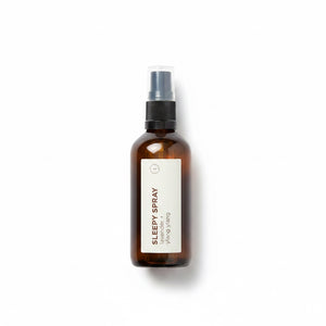 An amber glass spray bottle labeled 'SLEEPY SPRAY' by Yang Wang, featuring a black spray nozzle and a minimalist white label, set against a clean white background with a soft shadow.